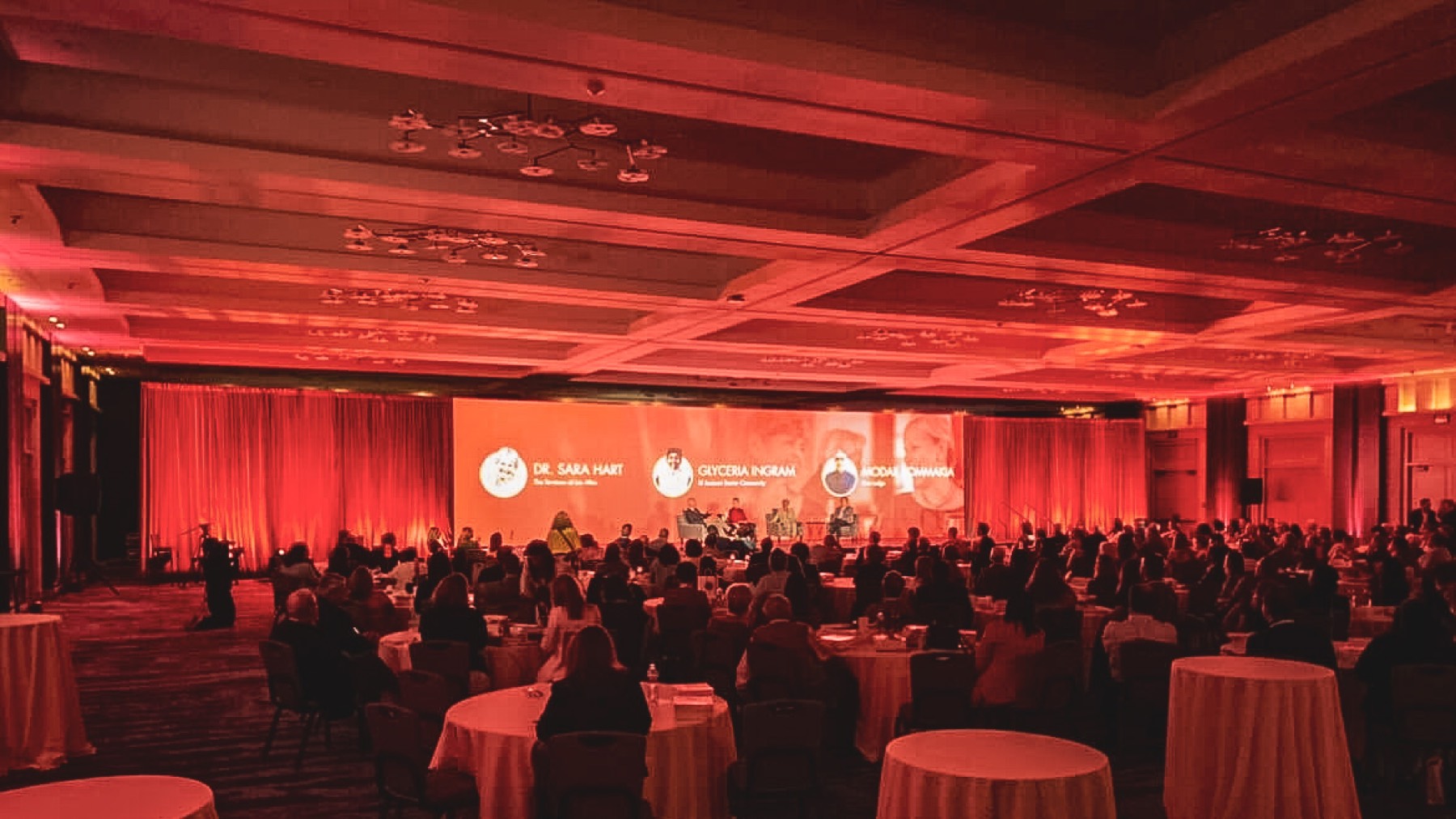 Panel discussion in a red-lit ballroom